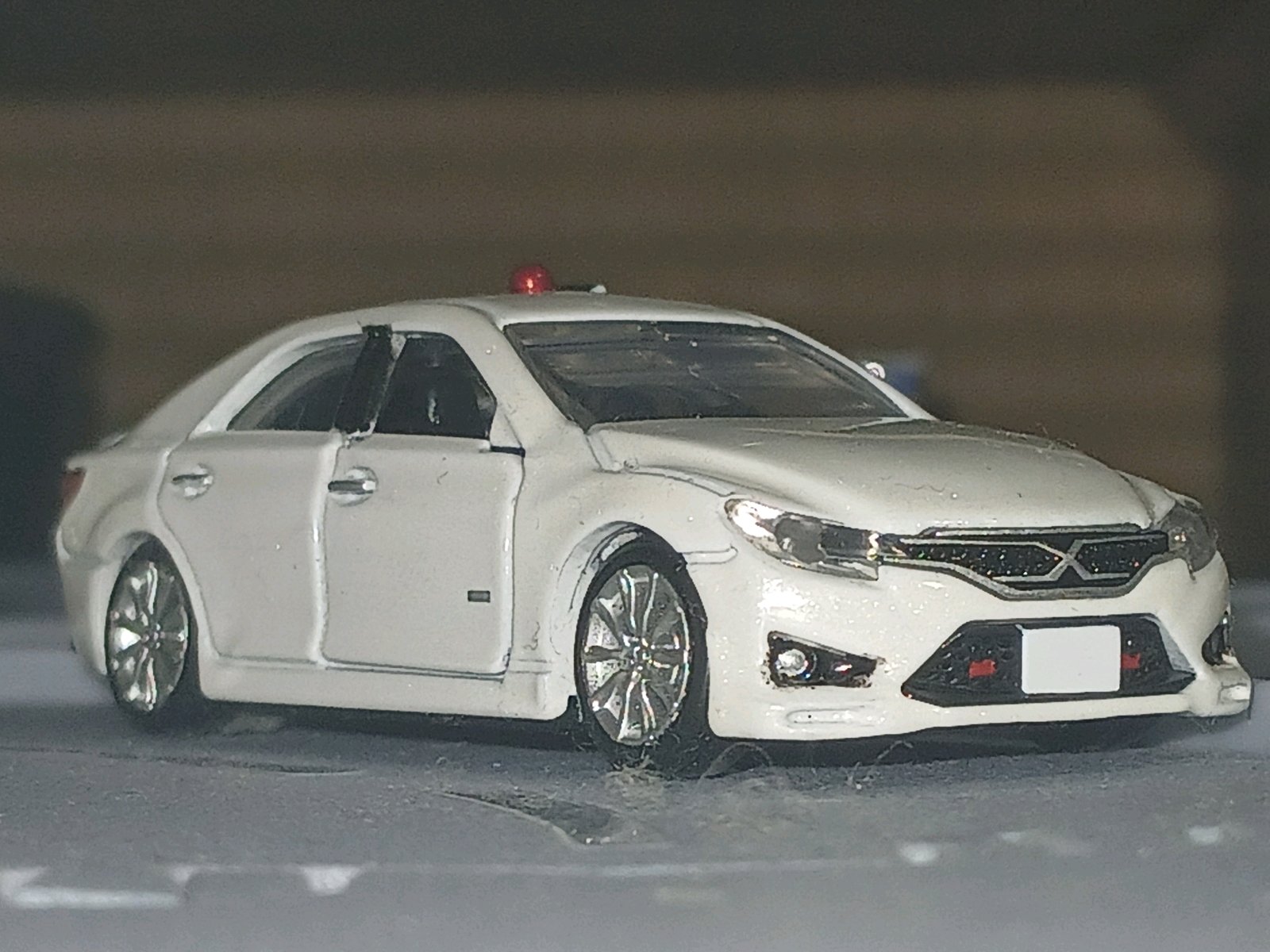 白いトヨタ・マークXのミニカー風モデルで、警視庁の覆面パトカーを再現した車両。赤色灯を備え、ドア開閉や赤色灯を隠せるギミックがあるTRD Mスーパーチャージャー仕様として紹介されている。