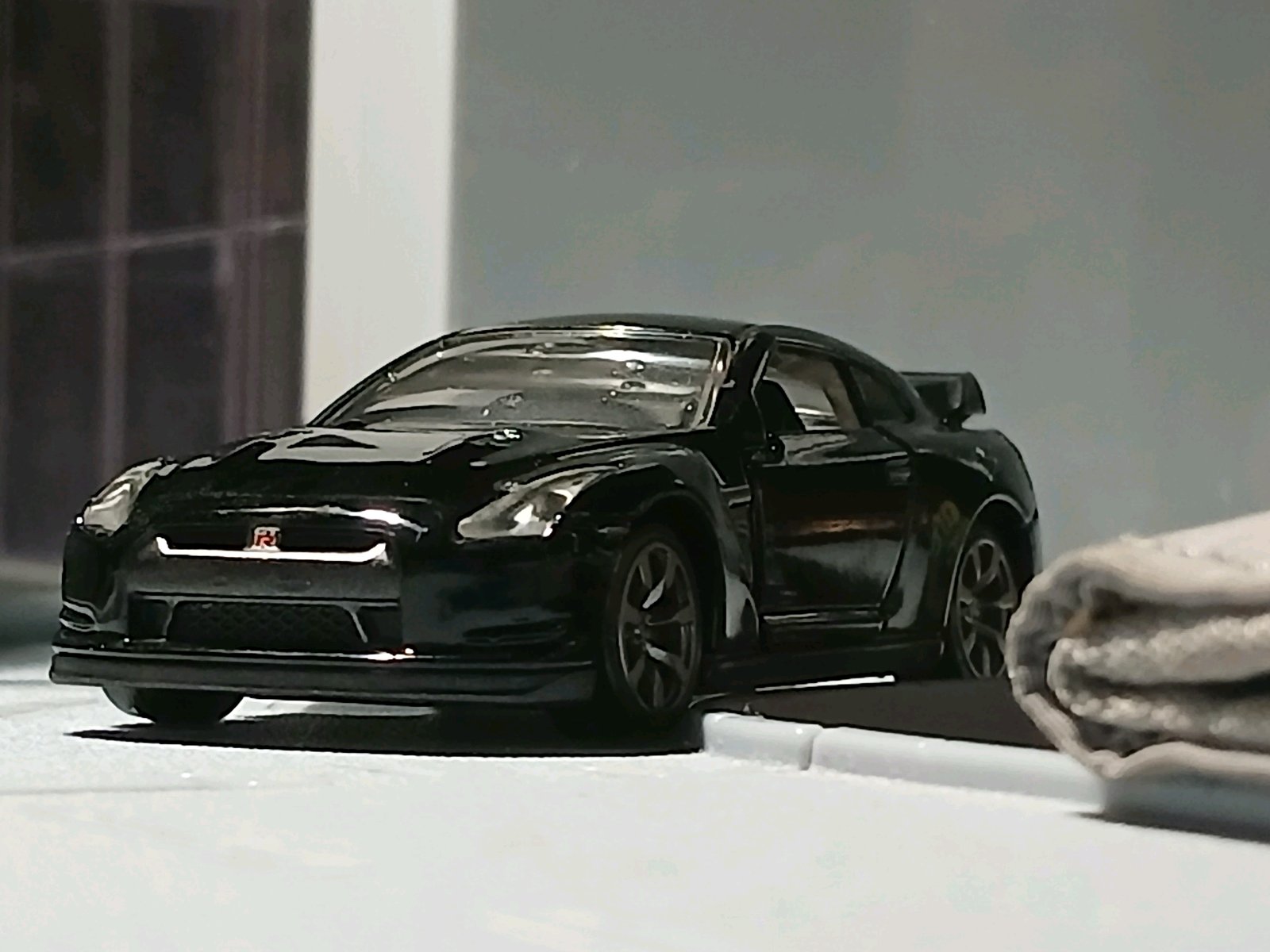 黒いNISSAN GT-R(07年モデル)のミニカーが室内に置かれており、前方斜めから低い視点で撮影されている。文脈どおり、480馬力の4WDスポーツカーGT-Rを紹介する投稿用の画像。